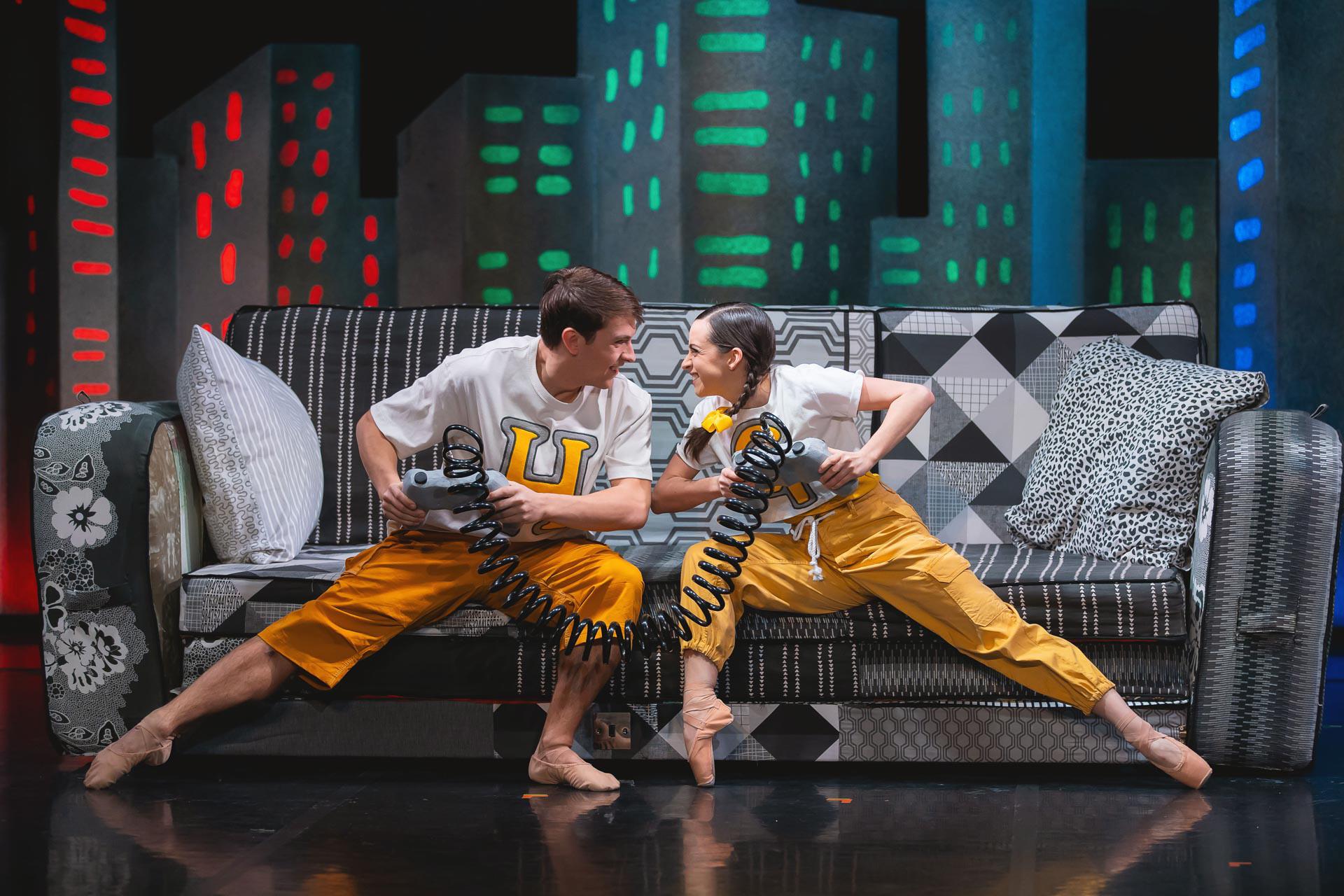 Two dancers on the edge of the sofa playing video games